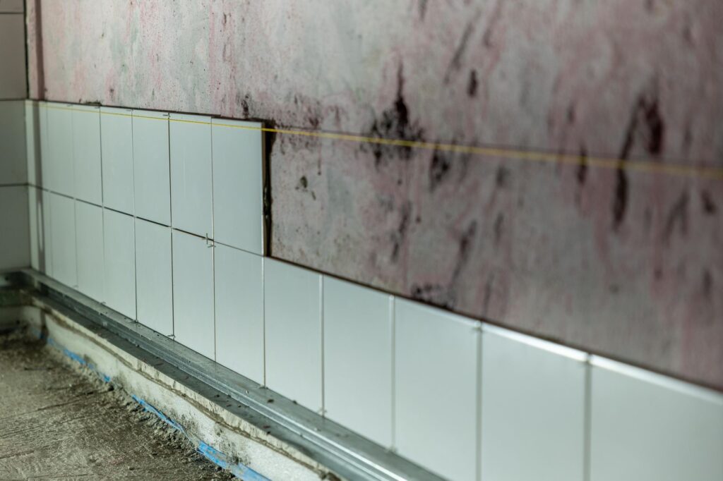 Pared de baño en obra con azulejos blancos colocados a media altura