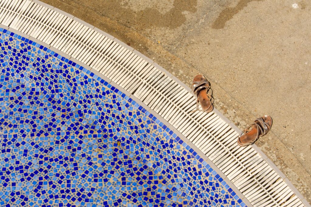 Borde de piscina con azulejos de mosaico azul y zona de pie descalzo